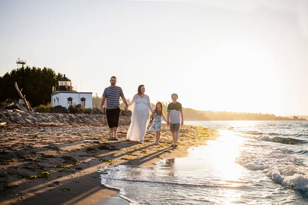 family of four holding hands and walking on the beach - couple human pregnancy sunset walking imagens e fotografias de stock