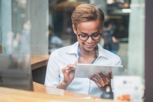 istock Happy business woman using digital tablet behind large glass window 1268607889