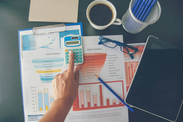 Woman working at home office desk using laptop business financial document chart and graph on wooden table with coffee cup. Woman freelance reading business graphs sale report on business office desk mujer que trabaja en el escritorio de la oficina en casa utilizando la tabla de documentos financieros de negocios portátiles y el gráfico sobre la mesa de madera con taza de café. mujer freelance leyendo gráficos de negocios informe de venta en oficin