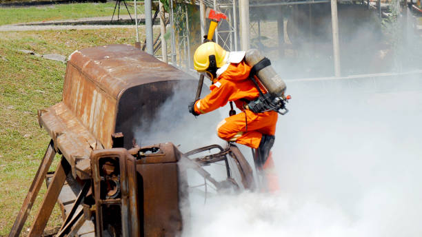 istock Firefighter fighting with flame using fire hose chemical water foam spray engine. Fireman wear hard hat, body safe suit uniform for protection. Rescue training in fire fighting extinguisher 1268612988