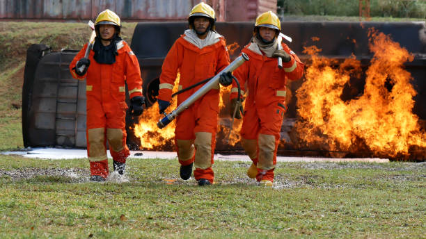 istock Firefighter fighting with flame using fire hose chemical water foam spray engine. Fireman wear hard hat, body safe suit uniform for protection. Rescue training in fire fighting extinguisher 1268613037