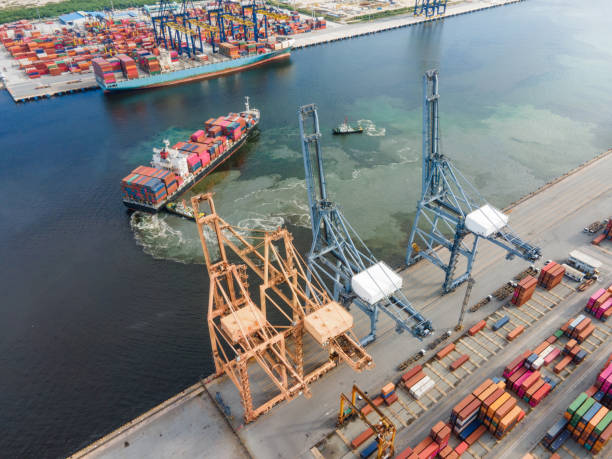 istock Logistics and import,export Container Cargo ship in asia working fro e-commerce business Shot by drone crane bridge in shipyard at sunset , logistic import export and transport industry background 1268613236