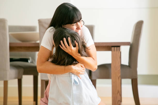 istock Happy mother embracing her lovely daughter with both hands 1268613981