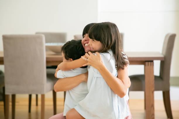 istock Happy mother hugging her lovely children with both hands 1268614383