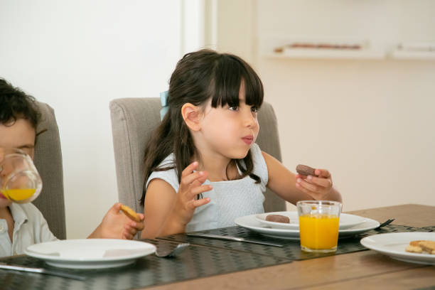 istock Cute little kids drinking juice and eating cookies at kitchen 1268615021