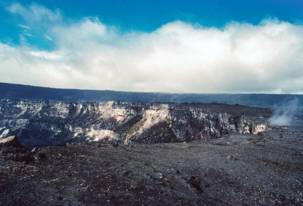This aerial drone photograph captures the stark and dramatic landscape of Hawaii Island, showcasing the intricate patterns of ancient lava flows. A deep fissure cuts across the terrain, revealing the raw geological forces that have shaped this volcanic landscape. Sparse vegetation dots the scene, highlighting the resilience of life in this rugged environment. We
