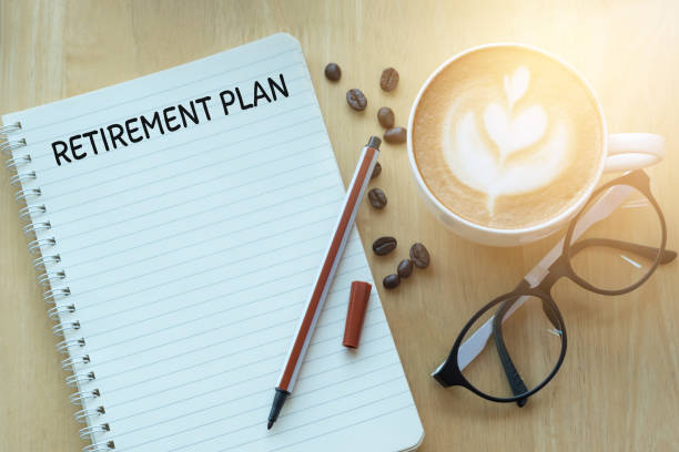 istock Retirement plan word on notebook with glasses, pencil and coffee cup on wooden table. Retirement plan concept. 1268624173