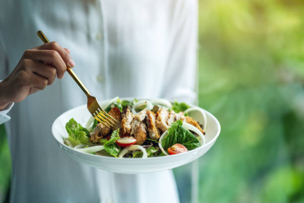 istock a woman holding and eating chicken salad 1268629014