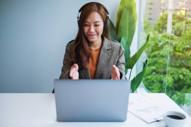 istock a beautiful businesswoman using headphone for video conference on laptop computer while working online 1268629027