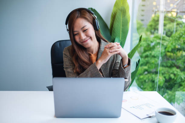 istock a beautiful businesswoman using headphone for video conference on laptop computer while working online 1268629072