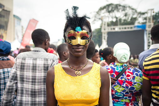Kampala / Uganda - October 4, 2016: Young African woman with yellow dress and carnival style mask in the street during Kampala Festival