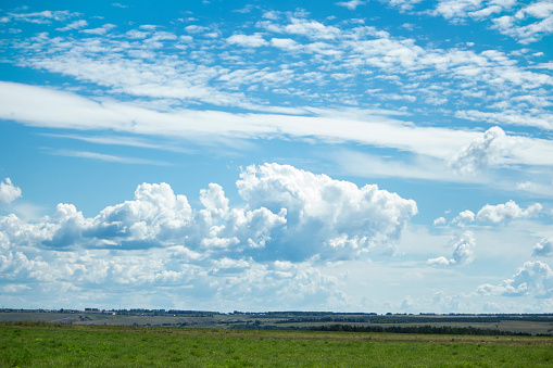 landscape with white clouds over green fields.