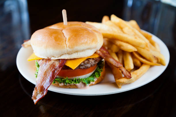 Bacon Cheeseburger with Fries Bacon Cheeseburger and fries served on a white plate. bacon cheeseburger stock pictures, royalty-free photos & images