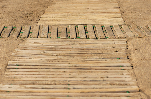 Close-up of an wooden walkways trough the sand on the beach