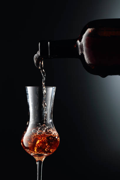 Strong golden alcoholic drink from the antique bottle being poured into a  glass. Strong golden alcoholic drink from the antique bottle being poured into a  glass. Copy space. sherry stock pictures, royalty-free photos & images