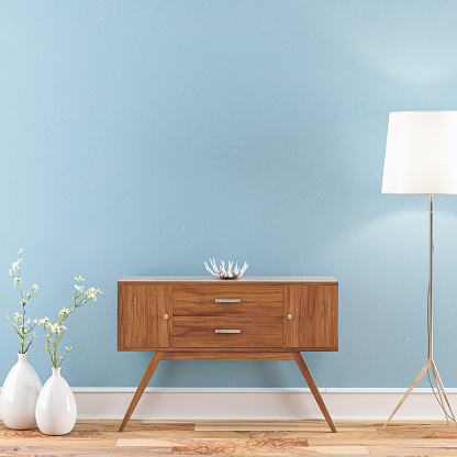 Empty pastel blue wall background on hardwood floor with a retro console table, electric lamp and decoration with copy space. 3D rendered image.
