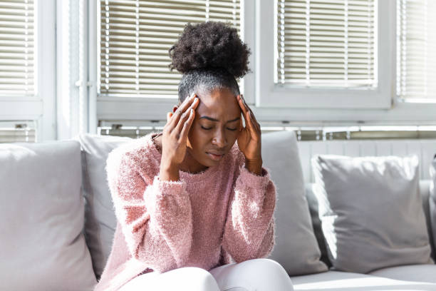 istock Depressed black young woman sit on sofa down upset having personal relationships problems, stressed millennial african American girl touch head feel despair mourning or grieving of loss 1268639791