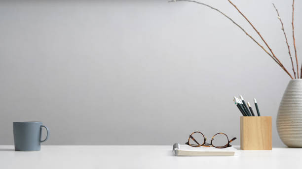 istock Study table with stationery, eyeglasses, notebook, mug, decoration and copy space in home office 1268640212