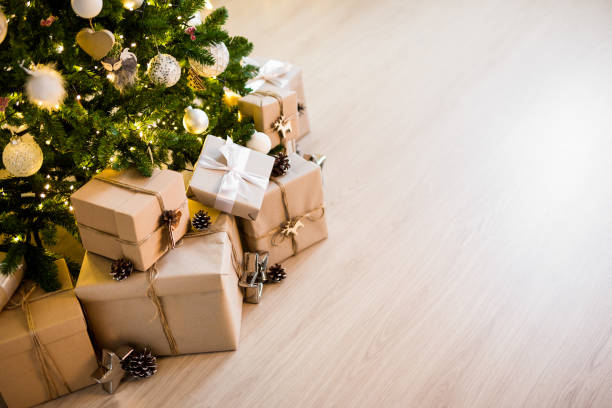 christmas tree and heap of gift boxes - copy space over wooden floor background stock photo