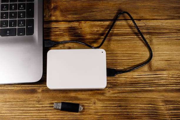 istock External HDD connected to laptop computer and USB flash drive on a wooden desk. Top view. Concept of data storage 1268640394