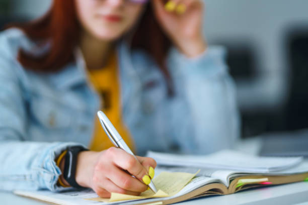 istock Young woman's hands holding pen and writing in daily planner. 1268643797