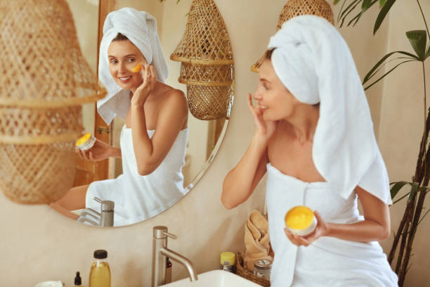 Woman Applying Clay Mask. Wrapped In Bath Towel Model Looking At Mirror And Using Skin Care Product For Derma. Morning Routine With Natural Cosmetic For Perfect Look. Woman Applying Clay Mask. Wrapped In Bath Towel Model Looking At Mirror And Using Skin Care Product For Derma. Morning Routine With Natural Cosmetic For Perfect Look. people covered in mud stock pictures, royalty-free photos & images