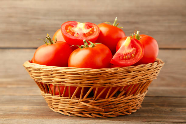 istock Ripe red tomatoes in basket on grey wooden background. 1268646016