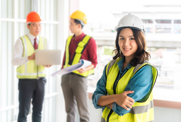 istock confidence Famale engineer standing portrait with two male engineer in background 1268648689