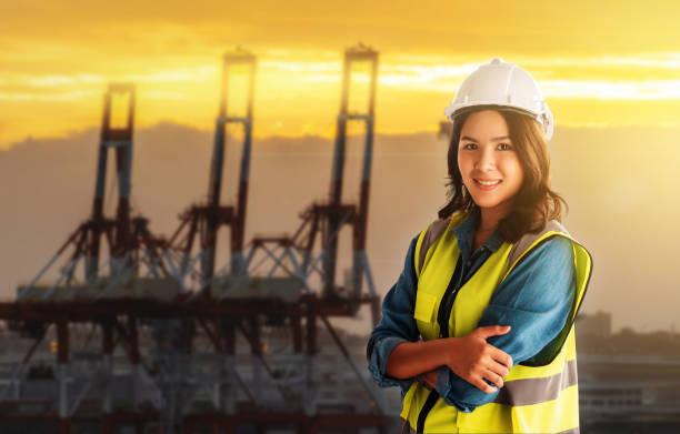 a engenheira está parada em frente para o terminal portuário de guindaste de carga. - industrial ship dock worker engineer harbor - fotografias e filmes do acervo