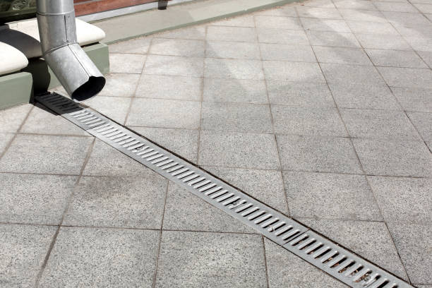 istock galvanized downspout on facade building with iron drainage grate of gray stone granite sidewalk from square tiles on ground, closeup details city infrastructure, nobody. 1268651462