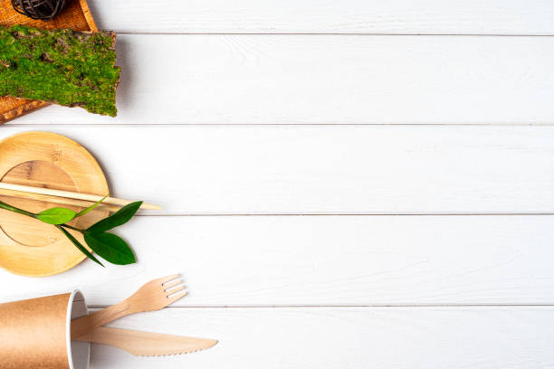 istock Flat lay Zero waste, eco friendly, natural organic plastic free concept. Green leaves, paper coffee cup and recycled tableware top view. Cutlery, earth, biodegradable with copy space on white wooden 1268653028