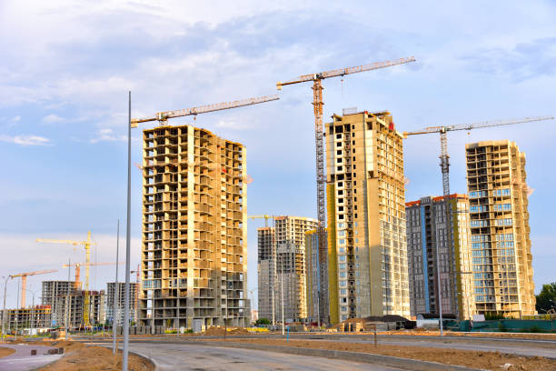 istock Tower cranes working at construction site on blue sky background. Construction process of the new modern residential buildings 1268653448