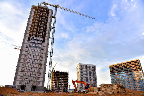 istock Large construction site with tower cranes and buildings on sunset background. Excavator during excavation for laying of underground storm sewer pipes 1268653603