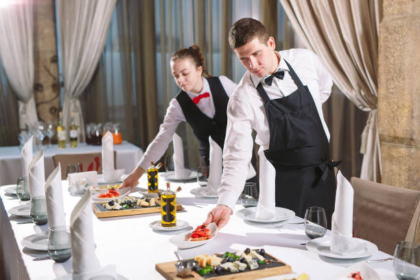 Waiters serving table in the restaurant preparing to receive guests stock photo