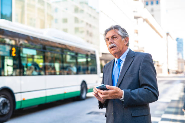 istock Senior Male Commuter Checking Smart Phone for Transportation 1268655343