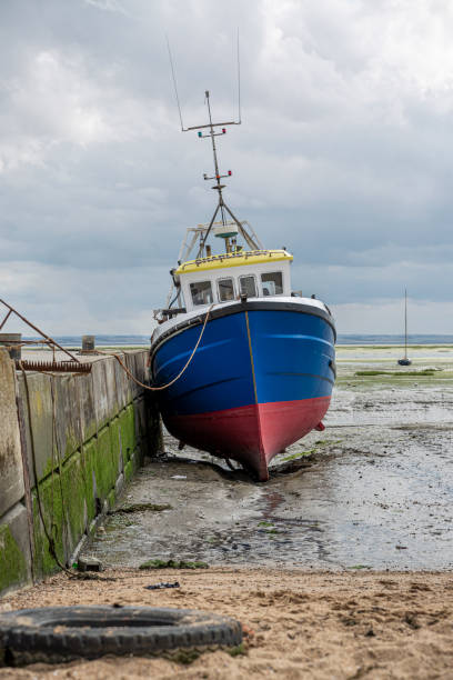 istock Fisherman blue boat stuck on the beach in low tide period. 1268657241