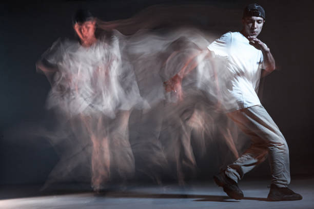 Stylish young guy breakdancer dancing in studio on black background. Long exposure shot. Battle competition announcement. High quality photo