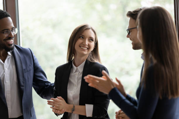 Diverse millennial colleagues meeting new female teammate in office Laughing employees warmly welcoming young lady intern on workplace, friendly teammates congratulating woman coworker with promotion, partners praising businesswoman for creating successful project employee introduction stock pictures, royalty-free photos & images