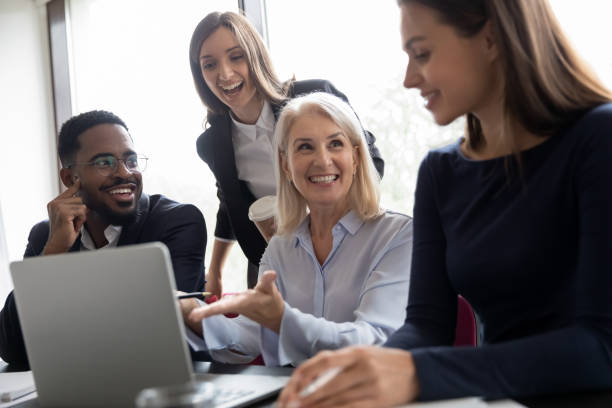 istock Elder female mentor teaching interns to create project on laptop 1268659504