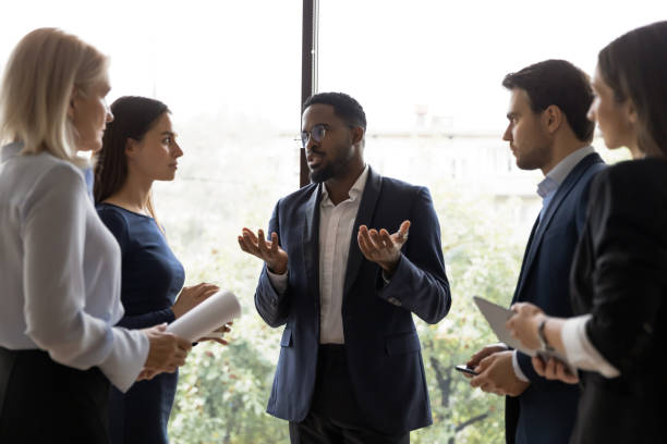 istock Black team leader talking to diverse subordinates at informal meeting 1268659521