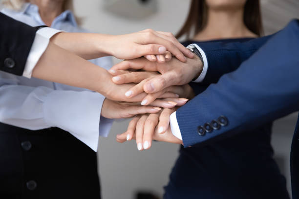 istock Group of diverse colleagues stacking hands together 1268659540