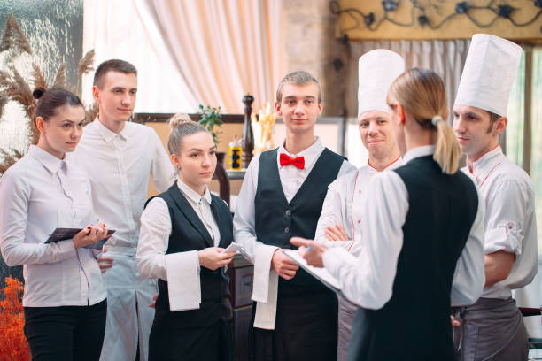 restaurant manager and his staff in kitchen. interacting to head chef in commercial kitchen. stock photo