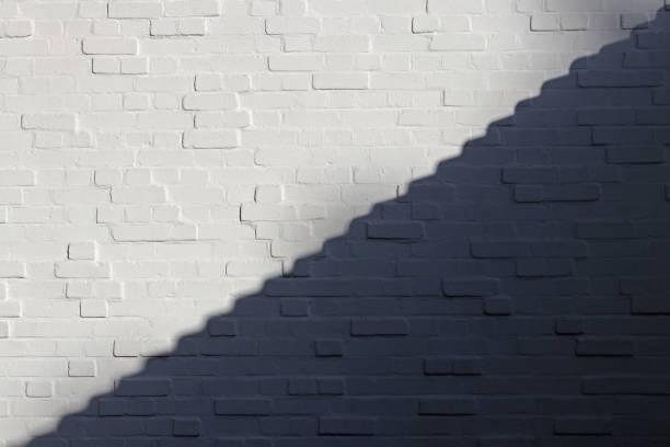 белая кирпичная стена разделена на светлые и теневые части по диагонали в виде ступеней. белое и черное. - yin yang symbol фотографии стоковые фото и изображения