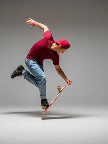 istock Cool young guy skateboarder stands on skateboard in studio isolated on gray background. Skateboarding tricks 1268661847