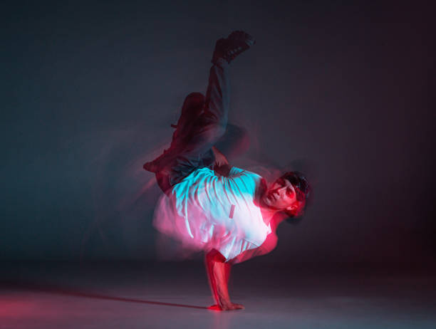 istock Cool young guy breakdancer dancing hip-hop on the floor in neon light. Dance school poster. Long exposure shot 1268663074