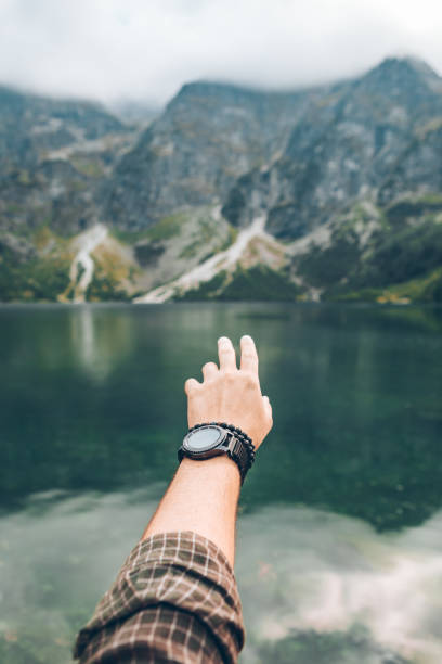 istock man hand showing beautiful lake in mountains 1268664639