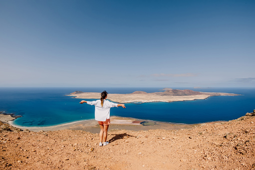 Happy traveller woman and scenic viewpoint to La Graciosa from Lanzarote island
