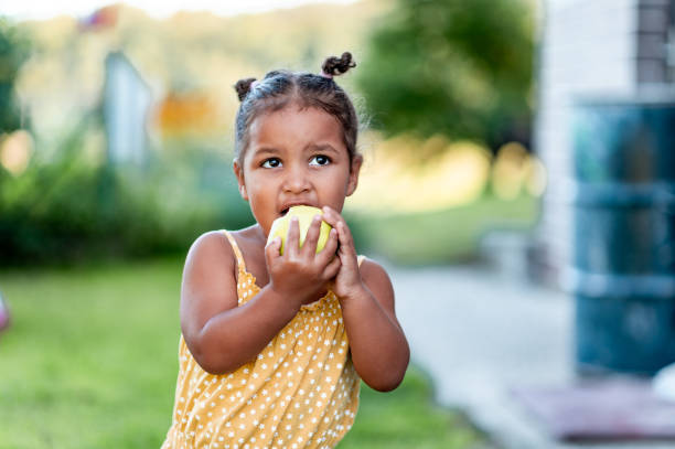 portret uroczej dziewczynki jedzącej jabłko na zewnątrz - apple eating little girls green zdjęcia i obrazy z banku zdjęć