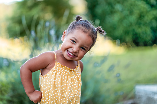 Portrait of a cute little cheerful mixed race girl in a yellow summer rummper.