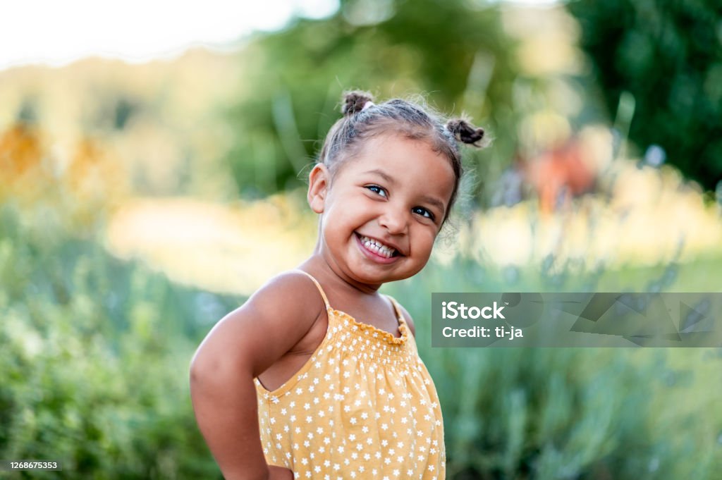 Portrait of cute little girl outdoors Portrait of a cute little cheerful mixed race girl in a yellow summer rummper. Child Stock Photo